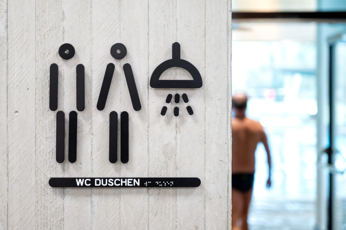 Nordbad Piktogramme Duschen und Toiletten mit taktiler Information auf Betonwand
